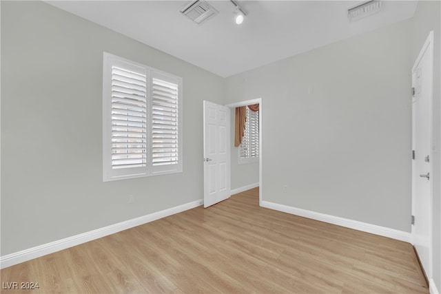 unfurnished bedroom featuring track lighting and light hardwood / wood-style flooring