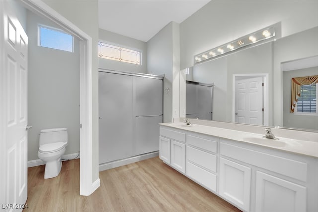 bathroom featuring hardwood / wood-style floors, vanity, a shower with door, and toilet