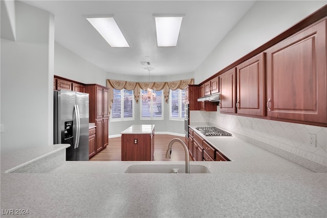 kitchen featuring pendant lighting, sink, decorative backsplash, appliances with stainless steel finishes, and a chandelier