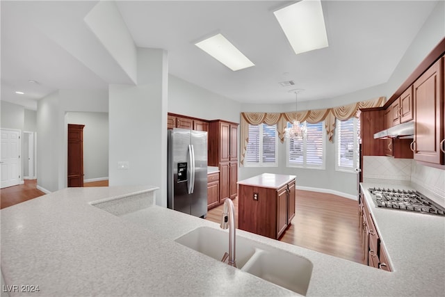 kitchen featuring light wood-type flooring, backsplash, stainless steel appliances, sink, and a chandelier