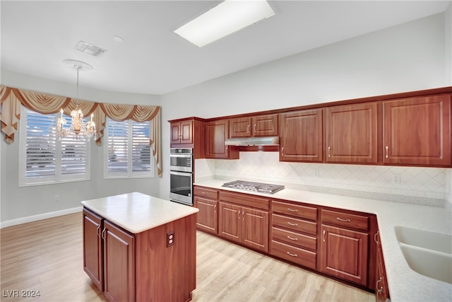 kitchen with backsplash, hanging light fixtures, stainless steel appliances, and light hardwood / wood-style floors