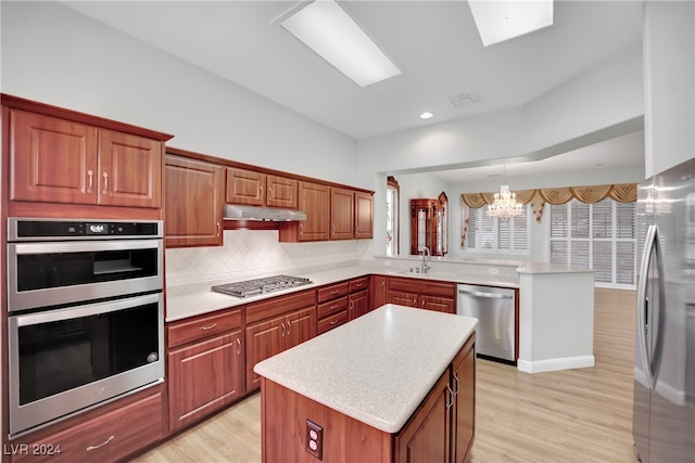 kitchen with a center island, light hardwood / wood-style floors, a notable chandelier, and appliances with stainless steel finishes