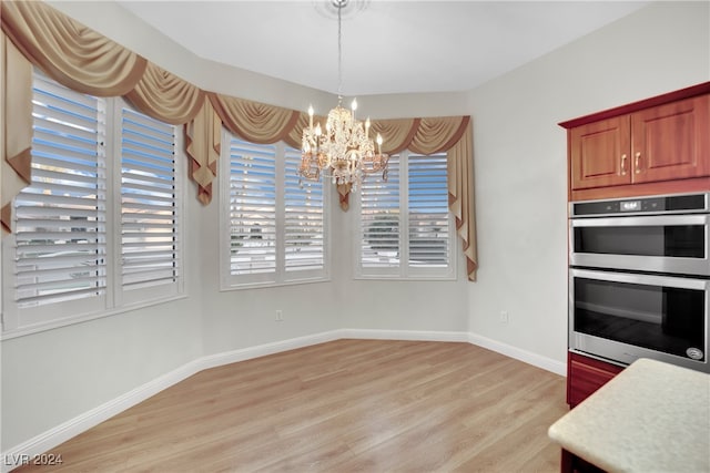 unfurnished dining area featuring light hardwood / wood-style floors and a notable chandelier