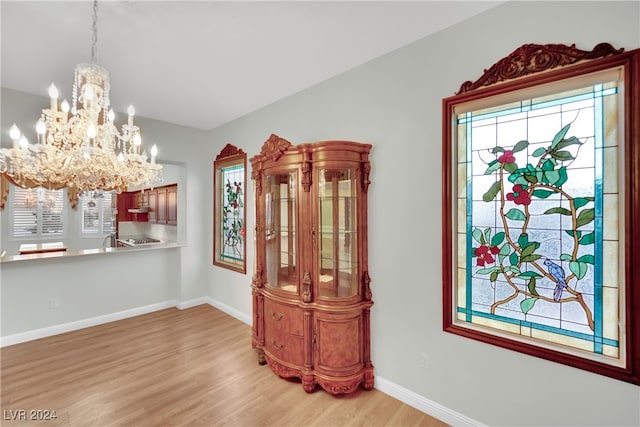 dining room featuring a wealth of natural light, sink, light wood-type flooring, and an inviting chandelier