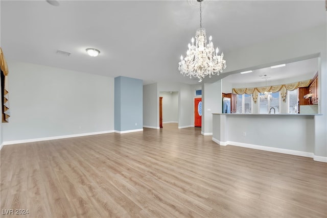 unfurnished living room with light hardwood / wood-style floors, an inviting chandelier, and sink