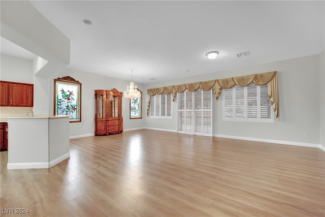 unfurnished living room featuring a notable chandelier, light hardwood / wood-style floors, and sink