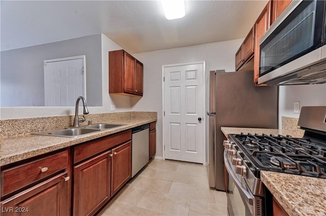 kitchen with appliances with stainless steel finishes, a textured ceiling, and sink