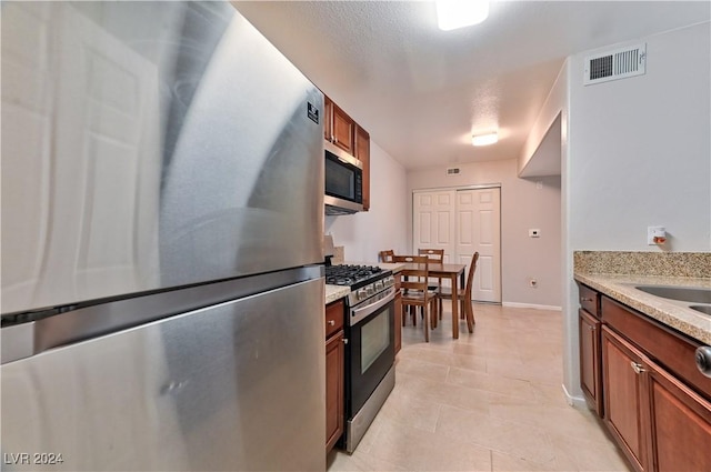 kitchen featuring light stone countertops, stainless steel appliances, and a textured ceiling