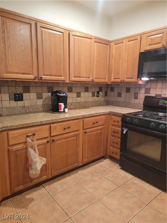 kitchen with tasteful backsplash, light stone counters, light tile patterned floors, and black appliances