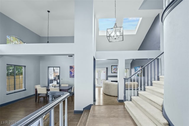 foyer entrance featuring a notable chandelier, dark wood-type flooring, and high vaulted ceiling