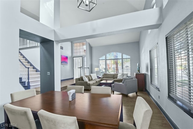 dining room with dark hardwood / wood-style flooring, high vaulted ceiling, and a notable chandelier