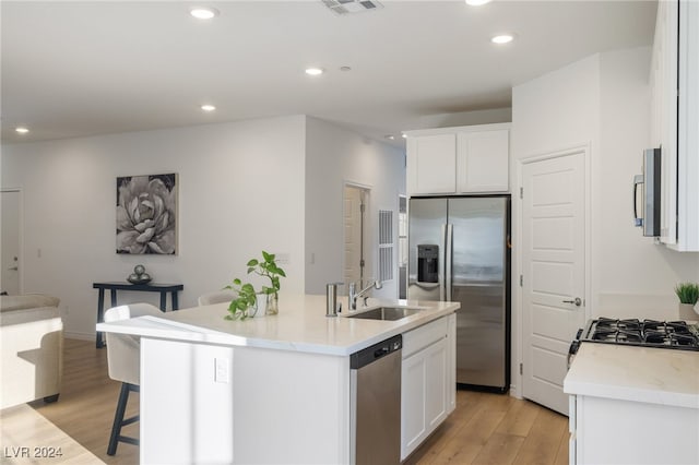 kitchen with white cabinets, appliances with stainless steel finishes, an island with sink, and sink