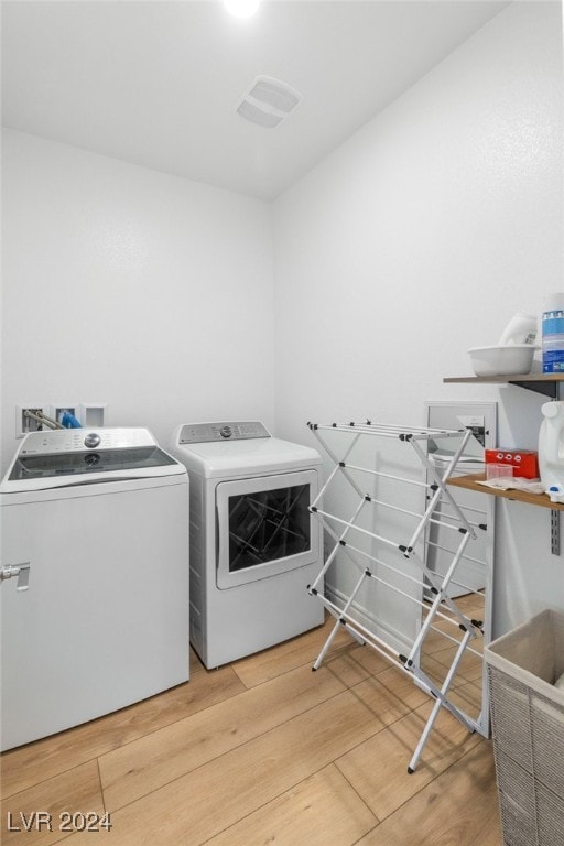 laundry area with wood-type flooring and washing machine and clothes dryer