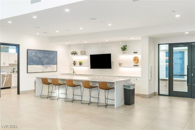 kitchen with white cabinets, a large island, dishwasher, and a breakfast bar area