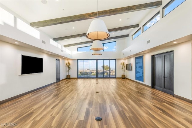 exercise room featuring hardwood / wood-style floors, a towering ceiling, and plenty of natural light