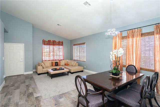 dining space featuring hardwood / wood-style floors, a notable chandelier, and vaulted ceiling