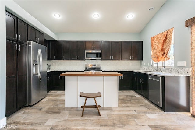 kitchen with decorative backsplash, stainless steel appliances, sink, a kitchen island, and a breakfast bar area