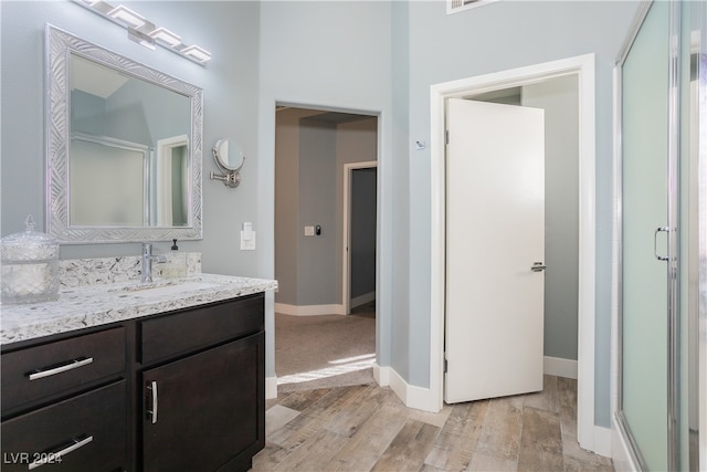 bathroom featuring vanity, an enclosed shower, and wood-type flooring