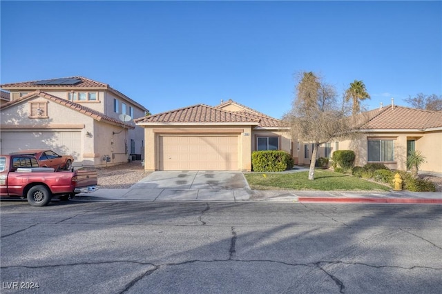 mediterranean / spanish-style home featuring a garage, a tiled roof, concrete driveway, and stucco siding