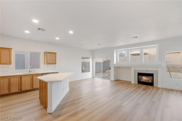 kitchen with light countertops, visible vents, open floor plan, a kitchen island, and a sink