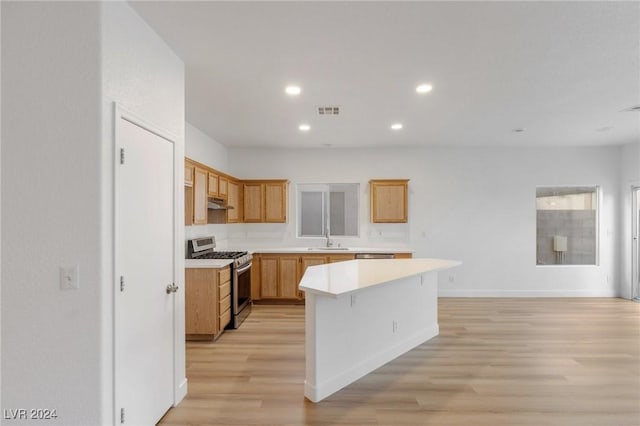 kitchen featuring visible vents, a center island, light countertops, stainless steel range with gas cooktop, and a sink