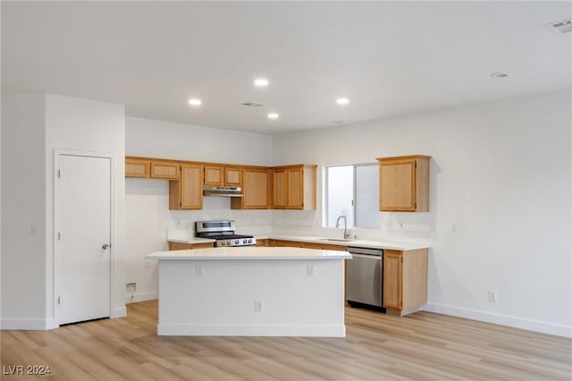 kitchen featuring light wood finished floors, stainless steel appliances, light countertops, a kitchen island, and a sink