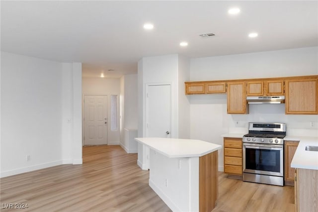 kitchen with stainless steel gas range oven, under cabinet range hood, visible vents, light countertops, and a center island