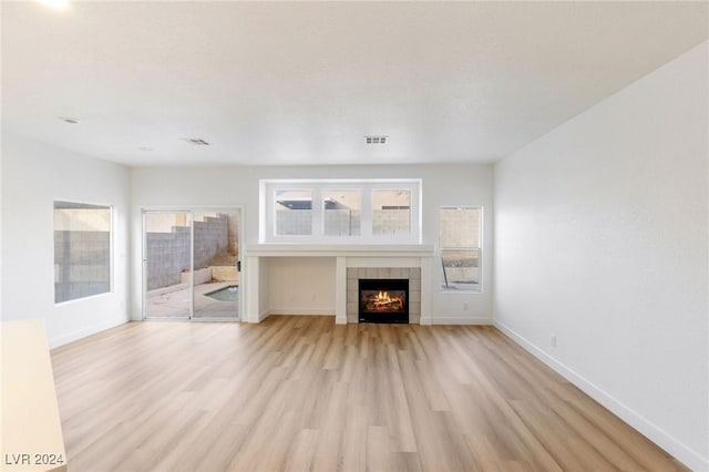 unfurnished living room featuring light wood-style floors, visible vents, a fireplace, and baseboards