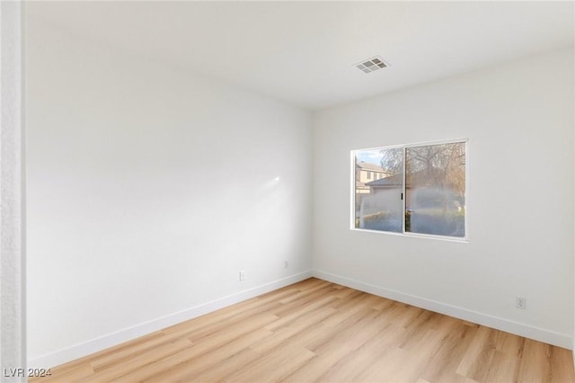 spare room with light wood-style flooring, visible vents, and baseboards