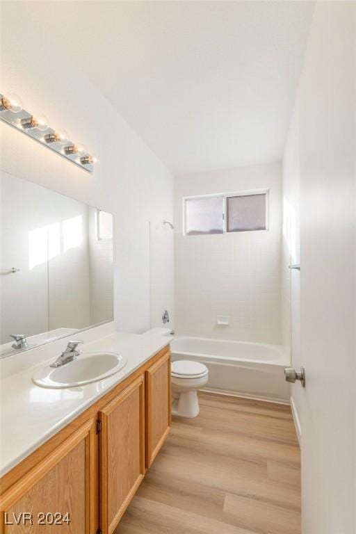 bathroom with toilet, wood finished floors, vanity, and a healthy amount of sunlight