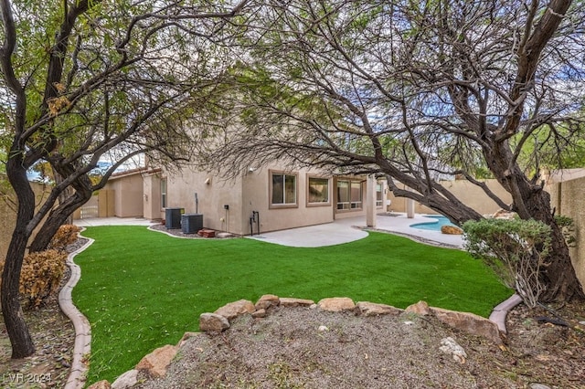 back of house with a lawn, central air condition unit, and a patio