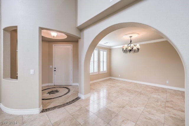 entryway with ornamental molding and a notable chandelier