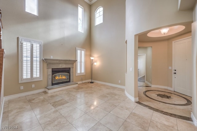 unfurnished living room featuring light tile patterned flooring and a towering ceiling