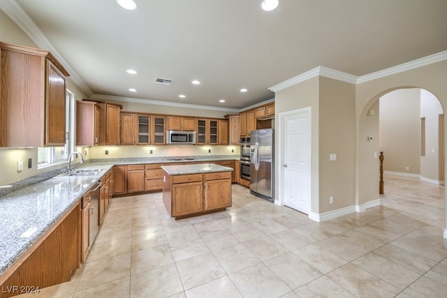 kitchen featuring light stone counters, a center island, sink, and stainless steel appliances