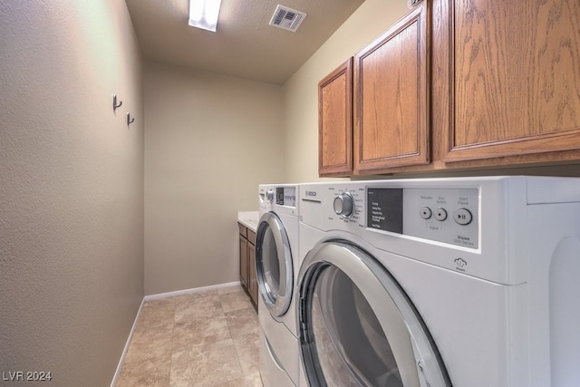 clothes washing area with washing machine and dryer and cabinets