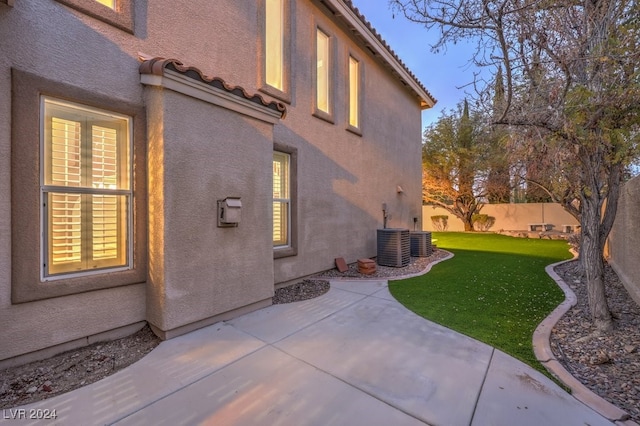 rear view of property featuring a patio, central AC unit, and a lawn