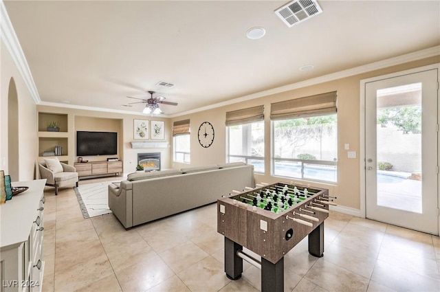 game room with built in features, ornamental molding, and a wealth of natural light