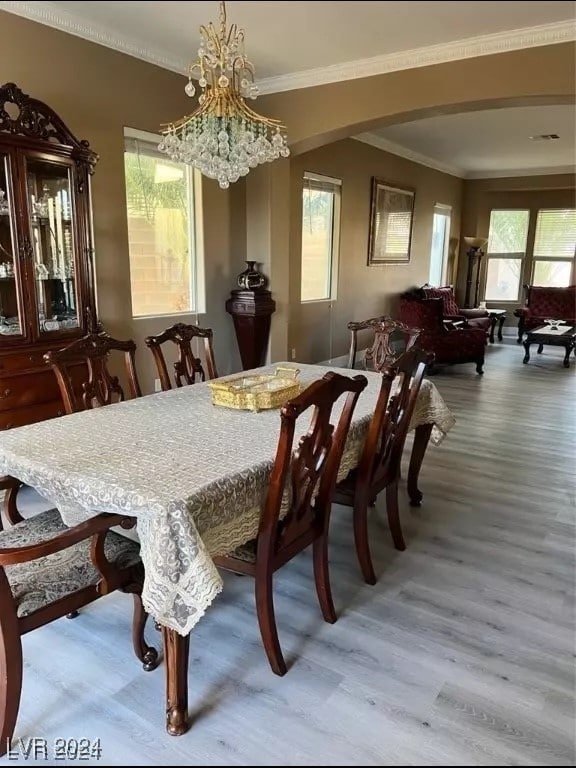 dining area featuring crown molding, hardwood / wood-style floors, and a notable chandelier