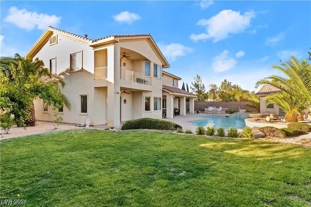 rear view of house with a balcony, a yard, a fenced in pool, and a patio area