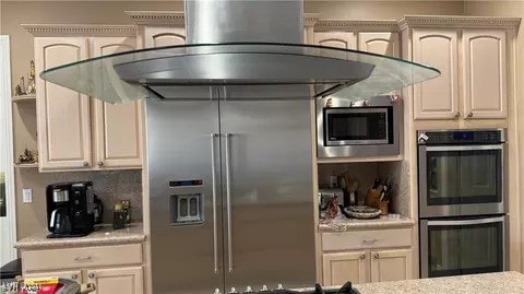 kitchen featuring built in appliances, tasteful backsplash, and island exhaust hood