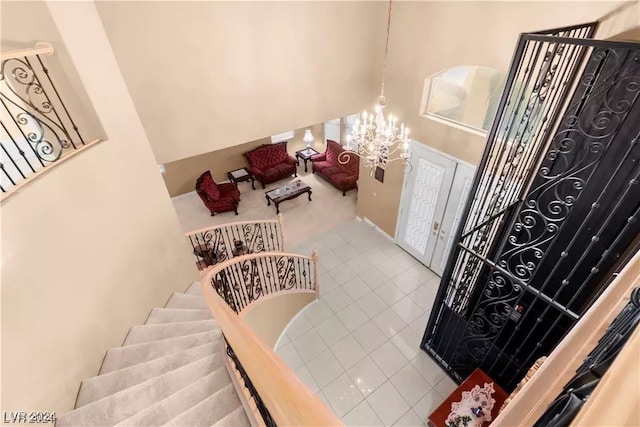 staircase featuring french doors, tile patterned floors, and a notable chandelier