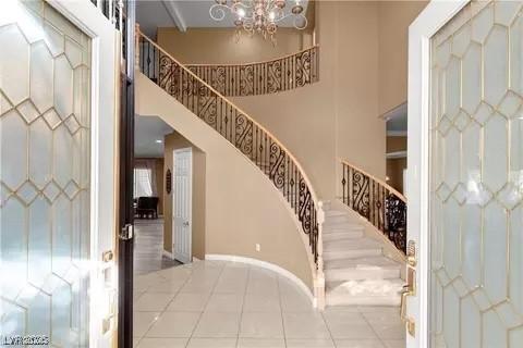 tiled entrance foyer with an inviting chandelier and a high ceiling