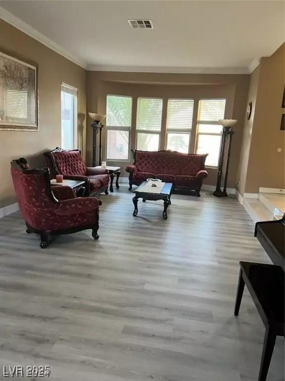 living room featuring plenty of natural light, ornamental molding, and light wood-type flooring