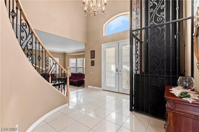 tiled entrance foyer featuring french doors, a notable chandelier, a high ceiling, and a wealth of natural light