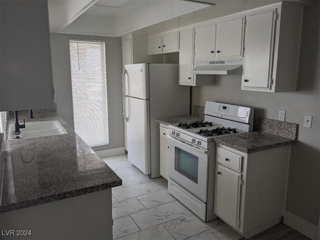 kitchen with sink, white cabinets, dark stone counters, and white appliances