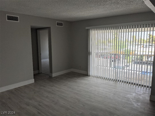 spare room featuring a wealth of natural light, a textured ceiling, and hardwood / wood-style flooring