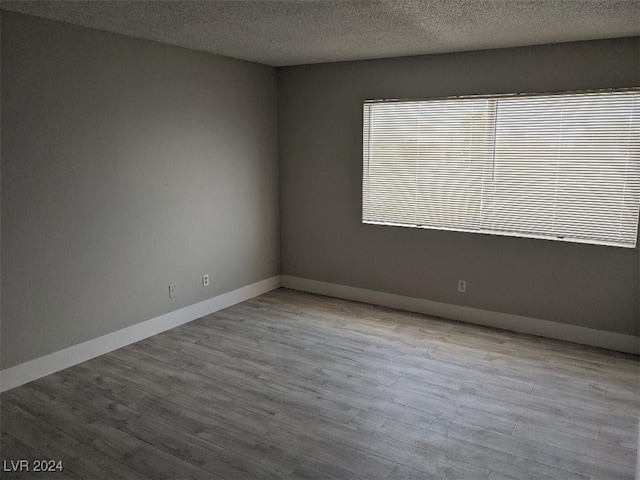 unfurnished room featuring a textured ceiling and light wood-type flooring