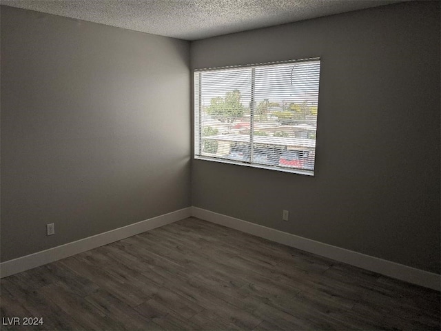 empty room with dark hardwood / wood-style flooring and a textured ceiling