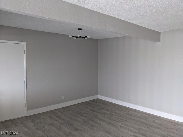 spare room with a textured ceiling and dark hardwood / wood-style floors