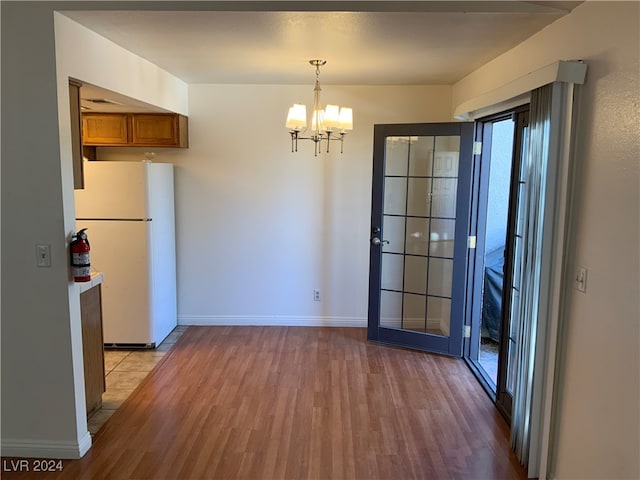 kitchen featuring a chandelier, white refrigerator, light hardwood / wood-style floors, and hanging light fixtures